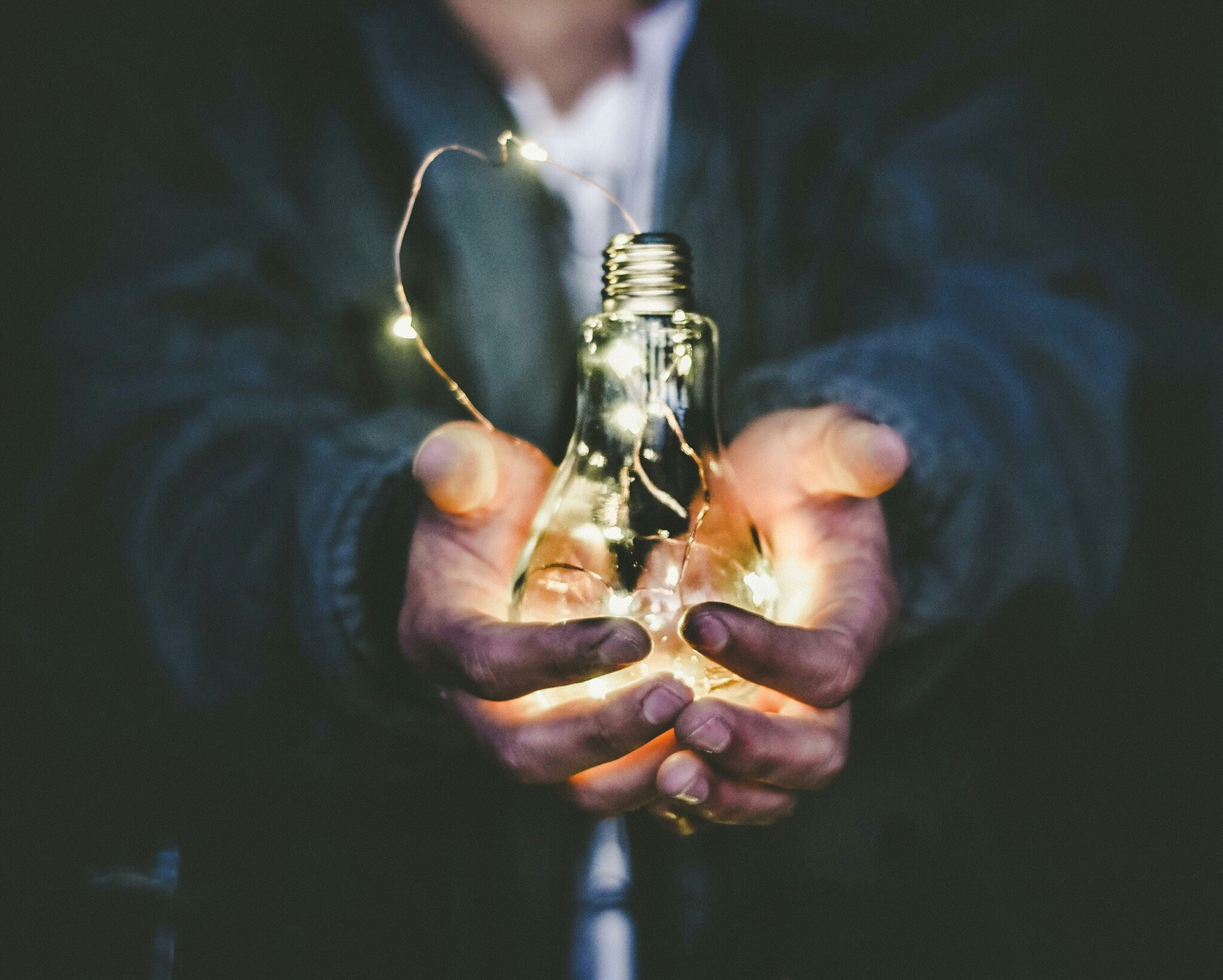 a light bulb in a person's hands representing unique ways to make money without investment